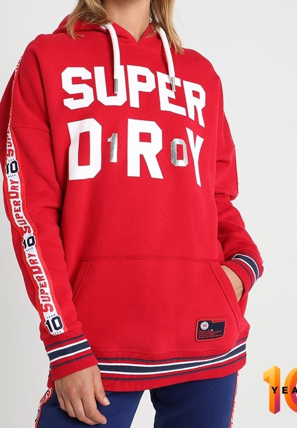 Rode hoodie met "SUPERDRY" in het wit aan de voorkant, voorzien van een kangoeroezak en gestreepte mouwen. Getextureerde stof met trekkoorden.