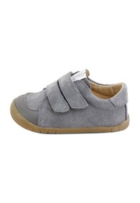 Zapato de ante gris con dos correas de velcro, puntera redondeada, suela de caucho y acentos en color beige. Superficie texturada con una puntera lisa.