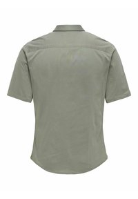 Chemise à manches courtes de couleur vert clair, avec un col, une texture lisse et un ourlet légèrement incurvé en bas. Vue de dos.