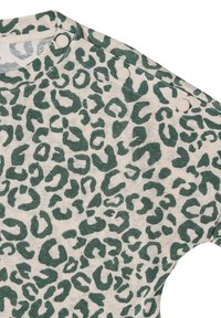 Tissu imprimé léopard vert avec trois boutons-pression beiges le long de la couture de l'épaule d'un vêtement.