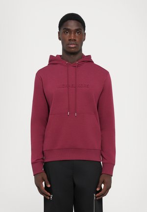Burgunderfarget hettegenser i mykt stoff med frontlomme og preget "Michael Kors"-logo. Har justerbare snorer og ribbestrikkede mansjetter.