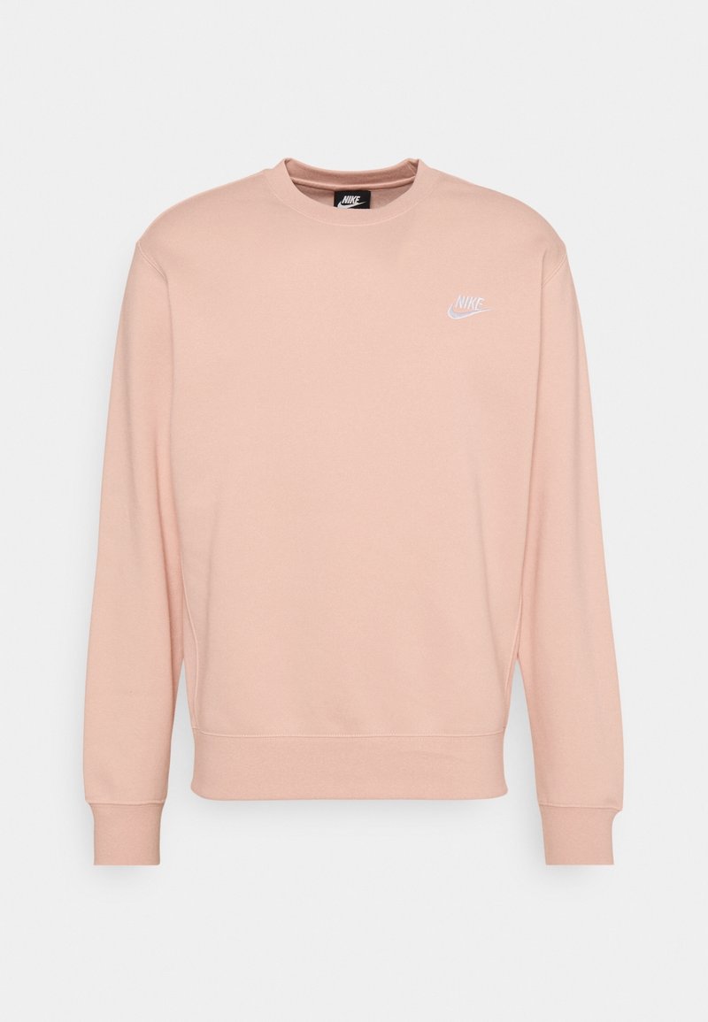 Světle růžový crewneck svetr Nike s dlouhými rukávy a malým bílým logem Nike na levé hrudi.