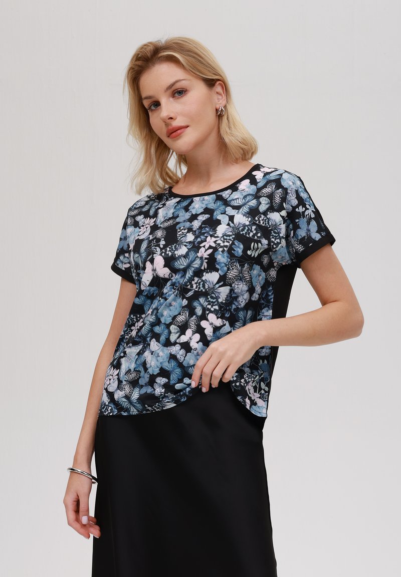 Top a maniche corte con stampa floreale in blu e nero, caratterizzato da una vestibilità rilassata e scollatura tonda. Tessuto liscio con parte inferiore a tinta unita in contrasto.