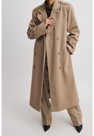 Cappotto doppiopetto in misto lana marrone chiaro, con spalline, una vestibilità sartoriale e rever a scollo. Abbinato a pantaloni coordinati.
