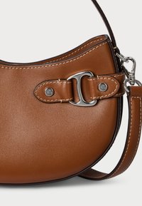 Pruun nahast käekott, millel on kaarjas kuju, hõbedased detailid ja kontrastne õmblus. Kaasas on eemaldatav õlavöö.