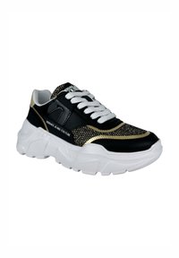 Sneaker nera con dettagli dorati e inserti in mesh, lacci bianchi, suola bianca spessa e logo sul lato. Parte superiore testurizzata per aderenza e stile.