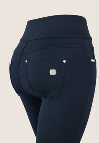 Leggings azul marino de cintura alta, con dos bolsillos traseros, accesorios de metal plateado y un acabado de tejido texturizado.