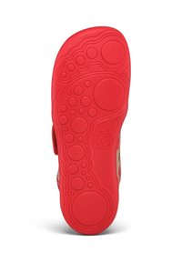 Suola di scarpa in gomma rossa con motivi circolari antiscivolo e una piccola faccia di animale in rilievo vicino al centro.