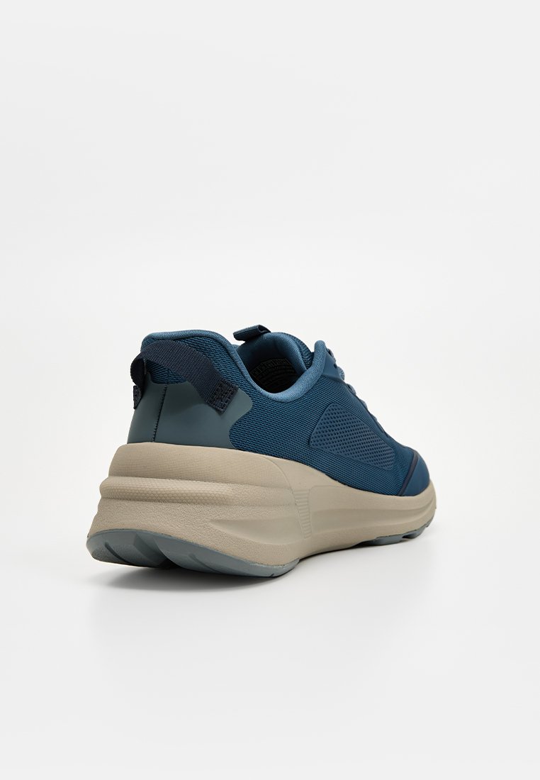 Scarpa sportiva blu con tomaia in rete testurizzata, collo imbottito e suola spessa beige. Presenta un tassello sul tallone per una facile calzata.