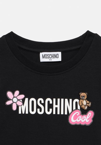 Μπλούζα παιδική για μαύρα παιδιά με ριμπ λαιμόκοψη, διακοσμημένη με το κείμενο "MOSCHINO", ροζ λουλούδι, αρκουδάκι και τις λέξεις "Cool" σε ροζ κεντητά πατς.
