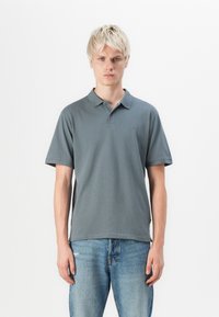 Grå kortærmet polo-shirt med krave i klassisk stil, lavet af bomuld, med et diskret logo på brystet og en afslappet pasform, parret med blå jeans.