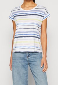 Pruhované bavlněné tričko s kulatým výstřihem, s modrými, černými, žlutými a růžovými vodorovnými pruhy na bílém pozadí.