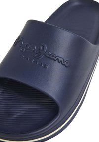Merenneidon sininen liukusandaali, joka on valmistettu sileästä muovista ja jossa on teksturoitu pohja. Varustettu kohokuvioidulla "Pepe Jeans London" -logolla ja hienovaraisella valkoisella raidalla.