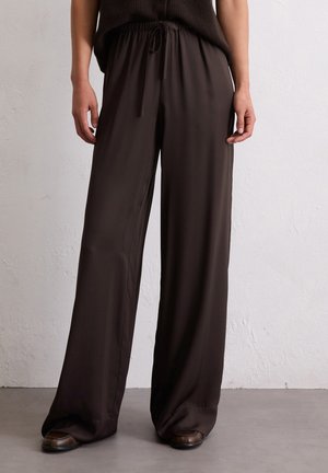 Wide-leg pants in dark brown, made from smooth, lightweight fabric with an elastic waistband and adjustable drawstring. Minimal detailing.