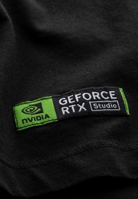 Zwarte stof met een gestikt etiket met groene accenten. Het etiket leest "NVIDIA GEFORCE RTX Studio" in witte tekst op een zwarte achtergrond.