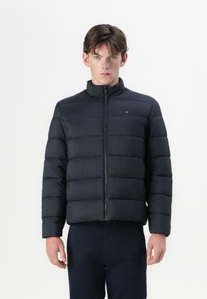 Chaquetón negro acolchado con acolchado horizontal, cuello alto y cremallera frontal. Presenta un pequeño logo en la parte superior izquierda.