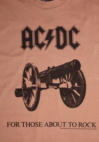 Hnědá bavlněná tričko s černým potiskem děla s koly a tučným textem "AC/DC" a "PRO TY, KTEŘÍ SE CHYSTAJÍ ROCKOVAT."