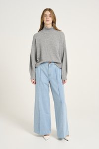 Gray turtleneck sweater with loose fit, paired with high-waisted light blue wide-leg jeans featuring front seams and a button closure.