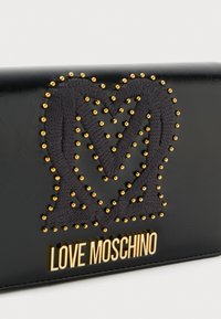 Portafoglio in pelle nera con un design di cuore ricamato grigio e borchie dorate. Il logo "LOVE MOSCHINO" è mostrato in lettere dorate.