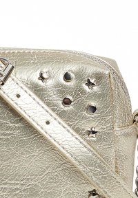 Bolso de piel sintética metálica dorada con un acabado texturizado, adornado con remaches en forma de estrella y en forma de círculo, y una correa de hombro desmontable.
