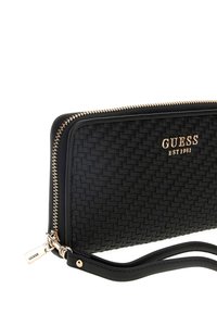 Portafoglio intrecciato nero con hardware dorato, dotato di chiusura zip, logo del marchio e tracolla removibile per il trasporto. Esterno in pelle testurizzata.
