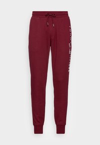 Burgunderfarbene Sweatpants mit elastischem Bund und Kordelzug. Mit seitlichem Logo-Print und schmal zulaufenden Bündchen. Hergestellt aus weichem, atmungsaktivem Stoff.