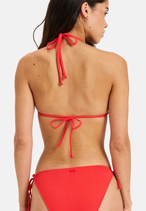 Red bikini with a textured pattern, featuring adjustable ties at the neck and sides. Fabric appears soft and lightweight.