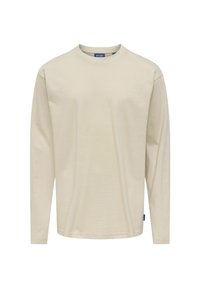 Beżowa bawełniana koszula z długim rękawem i okrągłym dekoltem. Posiada wszywane rękawy oraz małą niebieską metkę marki na dolnej stronie.