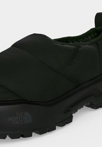 Μαύρο αθλητικό παπούτσι τύπου slip-on με καπιτονέ επάνω μέρος και ανθεκτική σόλα, με το λογότυπο The North Face στο πλάι.