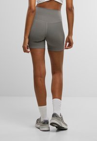 Shorts deportivos de talle alto en gris con un diseño ajustado, textura suave y costuras planas, combinados con zapatillas grises y calcetines blancos.