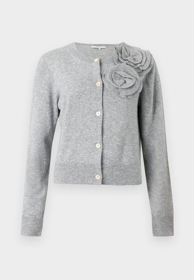 Ανοιχτό γκρι ζακέτα με κουμπιά, μακριά μανίκια και δύο μεγάλες υφασμάτινες διακοσμήσεις σε σχήμα λουλουδιού στον αριστερό ώμο.