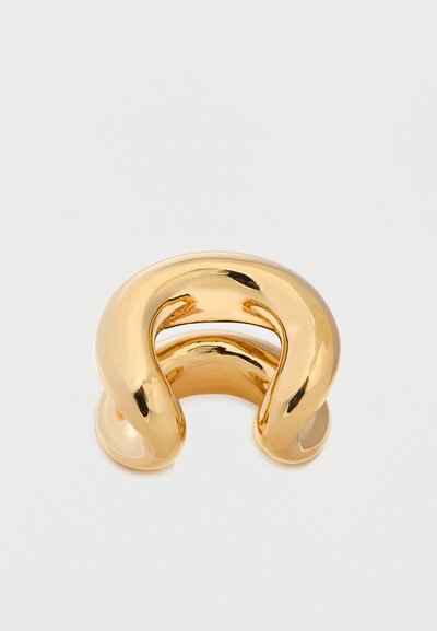 Dicker, glänzender Goldmanschettenarmband mit einem glatten, abgerundeten und offenen Design vor einem einfarbigen weißen Hintergrund.