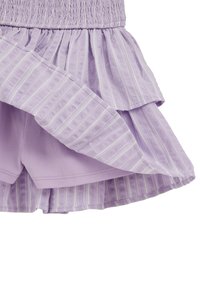 Lawendowa spódnica warstwowa z elastyczną talią i wbudowanymi spodenkami, z delikatnymi pionowymi białymi paskami na zewnętrznym materiale.
