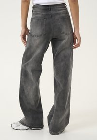 Wide-leg jeans in faded gray denim. Features two back pockets and a high waist. Tapered leg openings with a slightly distressed finish.