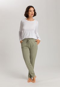 Top blanco de manga larga y joggers verde claro con cintura ajustable. Los joggers tienen bolsillos laterales y una textura suave y lisa.