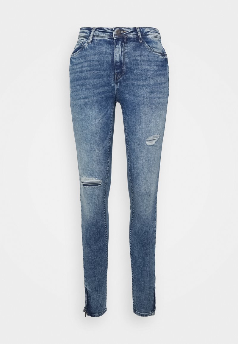 Jeans skinny em denim azul médio com um design desgastado, incluindo rasgos nos joelhos e zíperes nas bainhas para um ajuste ajustável.