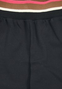 Black cotton fabric with a gathered waistband featuring horizontal stripes in pink, brown, white, and black at the top. Soft texture.