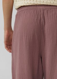 Pantalons mauves amples en tissu texturé avec une taille élastique. Le tissu a une apparence froissée, ajoutant de la profondeur au design.