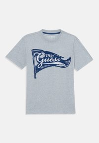Graues Baumwoll-T-Shirt mit kurzen Ärmeln, mit einem dunkelblauen Grafikdesign eines Flags und dem Text "Guess 1981". Klassischer Rundhalsausschnitt.