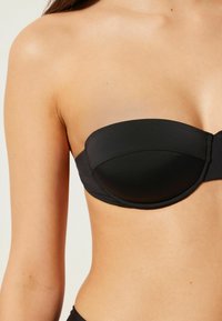 Svart strapless bikiniöverdel med formade kupor, slät textur och sömlös design för en smidig passform. Lämplig för simning och strandkläder.