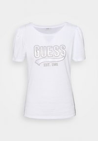 Camiseta de algodón de manga corta blanca, con "GUESS" bordado en hilo metálico y "EST. 1981" debajo, cuello redondo y mangas abullonadas.
