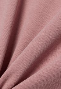Soft pink fabric with a smooth texture, featuring a knit pattern and gentle folds that create depth and dimension.