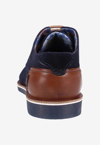 Chaussure de ville pour homme en suede marine et cuir brun vue de l'arrière, avec une doublure en tissu à motifs et une semelle noire avec une bande blanche.