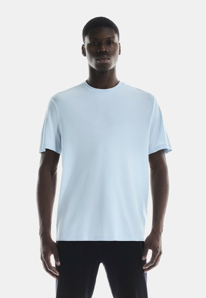 Lyseblå kortærmet t-shirt lavet af glat stof med rund hals; har en afslappet pasform og et enkelt design uden mønstre eller detaljer.