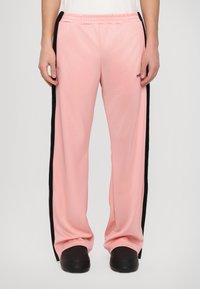 Ροζ αθλητικά παντελόνια με μαύρες λωρίδες στο πλάι, ελαστική μέση και χαλαρή εφαρμογή. Λείο ύφασμα με ελαφριά γυαλάδα και άνετο σχέδιο.