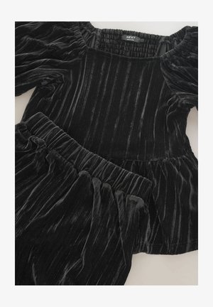 Černý sametový dvoudílný outfit s nařaseným výstřihem a nadýchanými rukávy. Vrchní část má peplum design a pás je elastický.