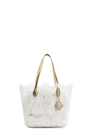 Hvid blonde-tote taske med gyldne håndtag og en gylden firkantet charme, der hænger fra et håndtag.