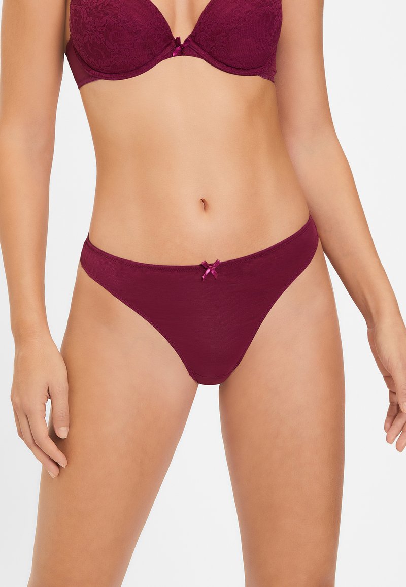 Bordeaux kanten bh en bijpassende stringset, met een zachte textuur, bloemenpatroon en klein satijnen strikje detail bij de tailleband.