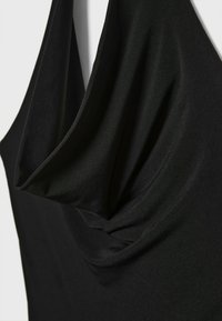 Crni top bez rukava s drapiranim dekolteom, izrađen od glatkog, laganog materijala s suptilnim sjajem i elegantnim naborima.
