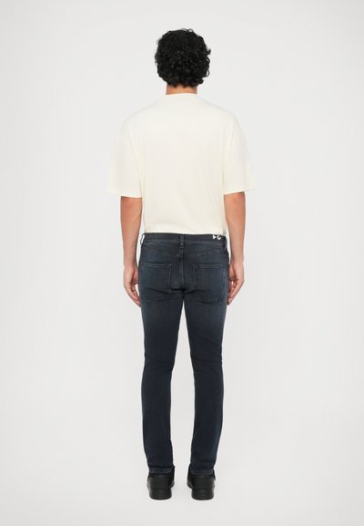 Vit kortärmad t-shirt som är ihopparad med mörkblå slim-fit jeans. Jeansen har en klassisk femfickdesign och en märkesbård i midjan.